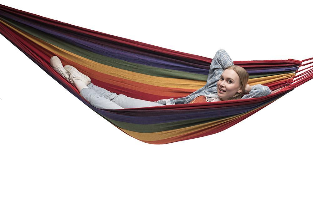 Woman relaxing in a colorful double Brazilian hammock against white background