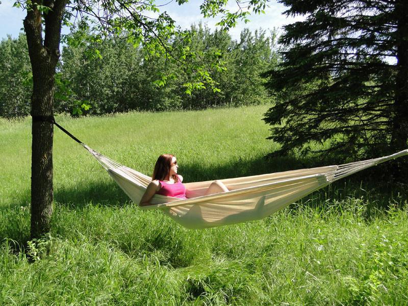 Woman relaxing in a Brazilian style double hammock outdoors in a grassy field