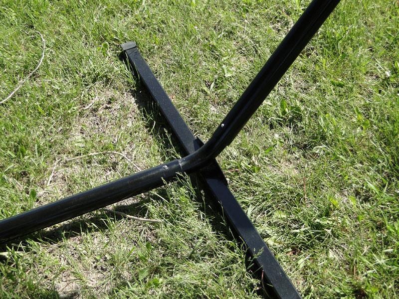 Black metal tri-beam hammock stand base on green grass outdoors