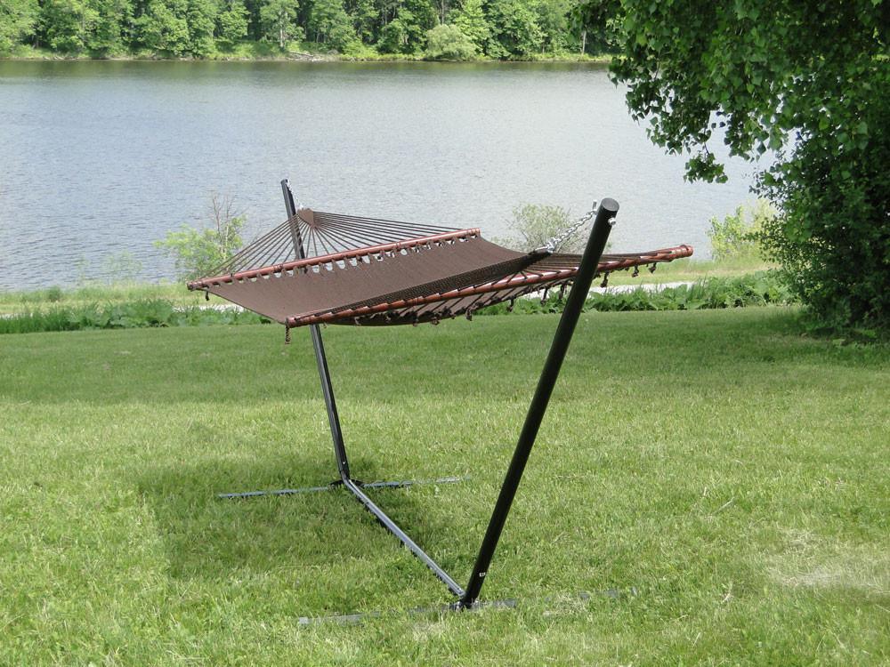 Polyester rope hammock with 3-beam metal stand on grass by a lake