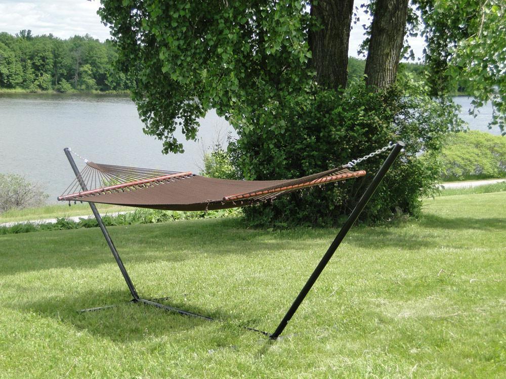 Polyester rope hammock with 3-beam stand on grass near trees and a lakeside view