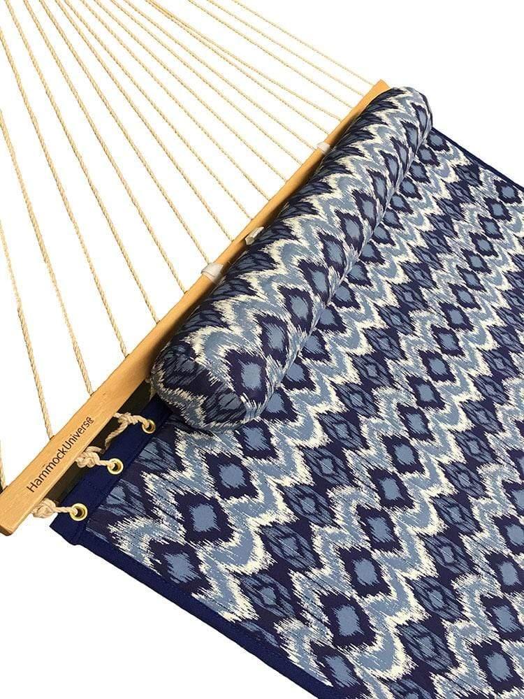 Closeup of quilted hammock with blue and white geometric patterns and wooden spreader bar