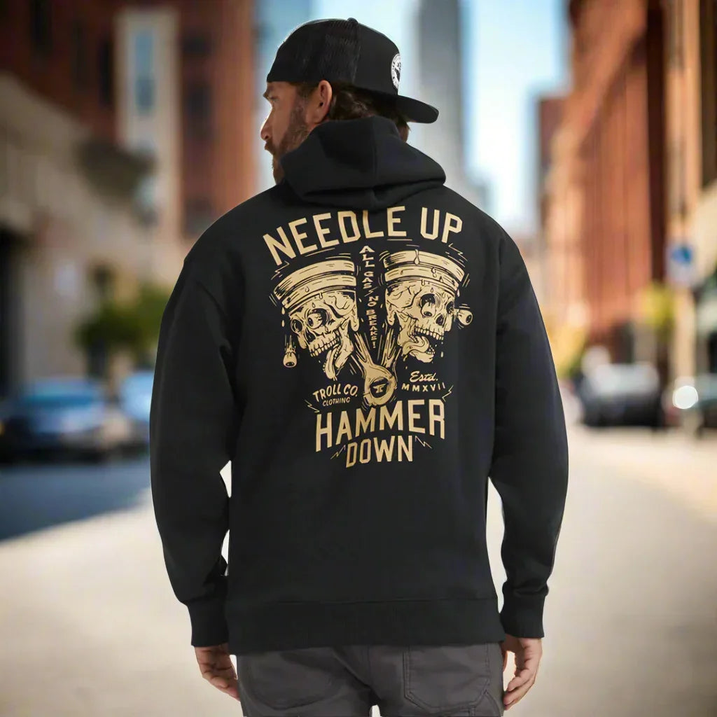 Man wearing black hoodie with 'Needle Up Hammer Down' piston skull graphic, city street
