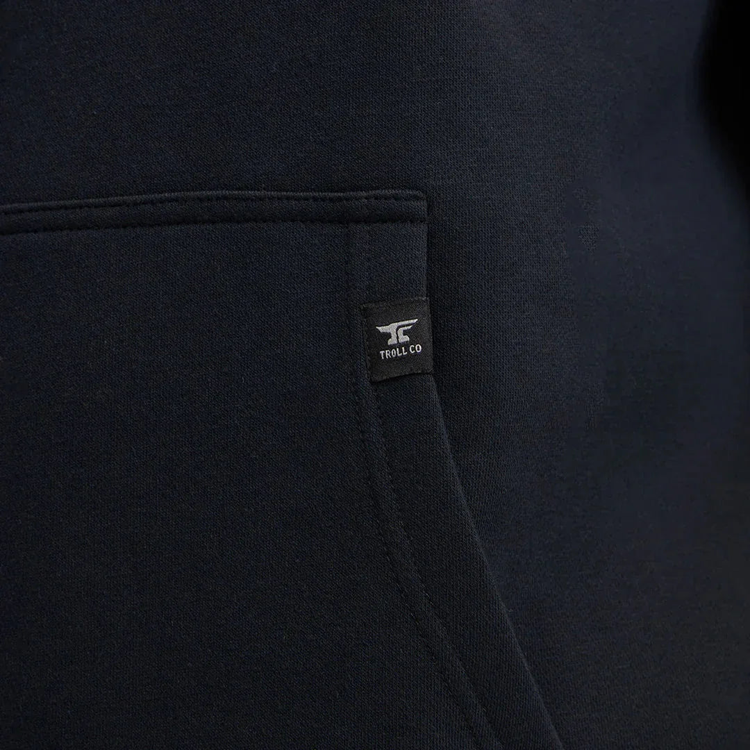Close-up of black Troll Co hoodie pocket with logo tag on soft fabric