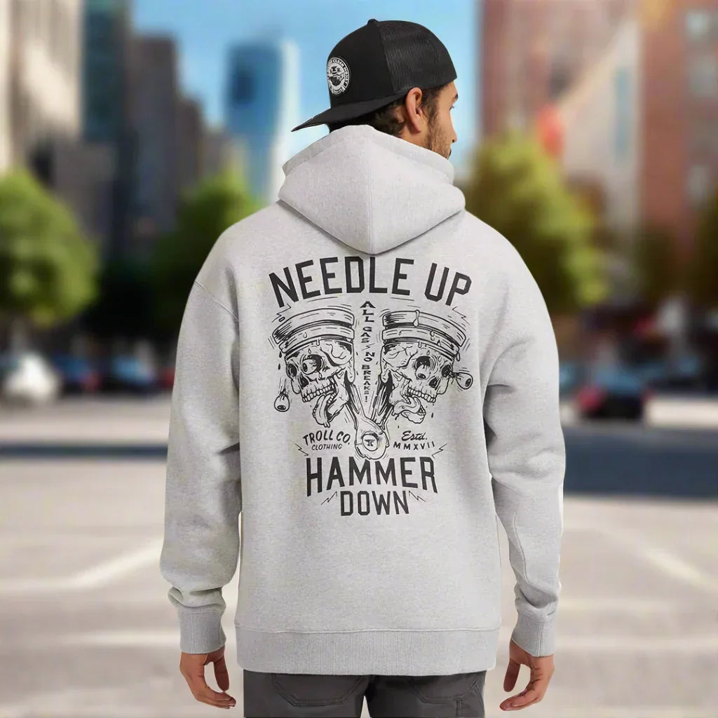 Man wearing grey hoodie with 'Needle Up Hammer Down' skull engine graphic on city street