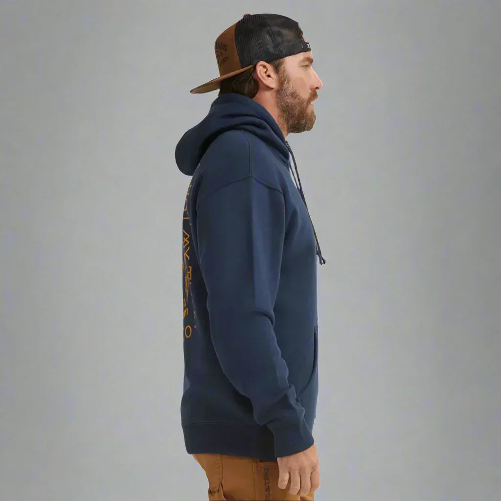 Man in navy hoodie and trucker cap side view, casual workwear, plain grey background