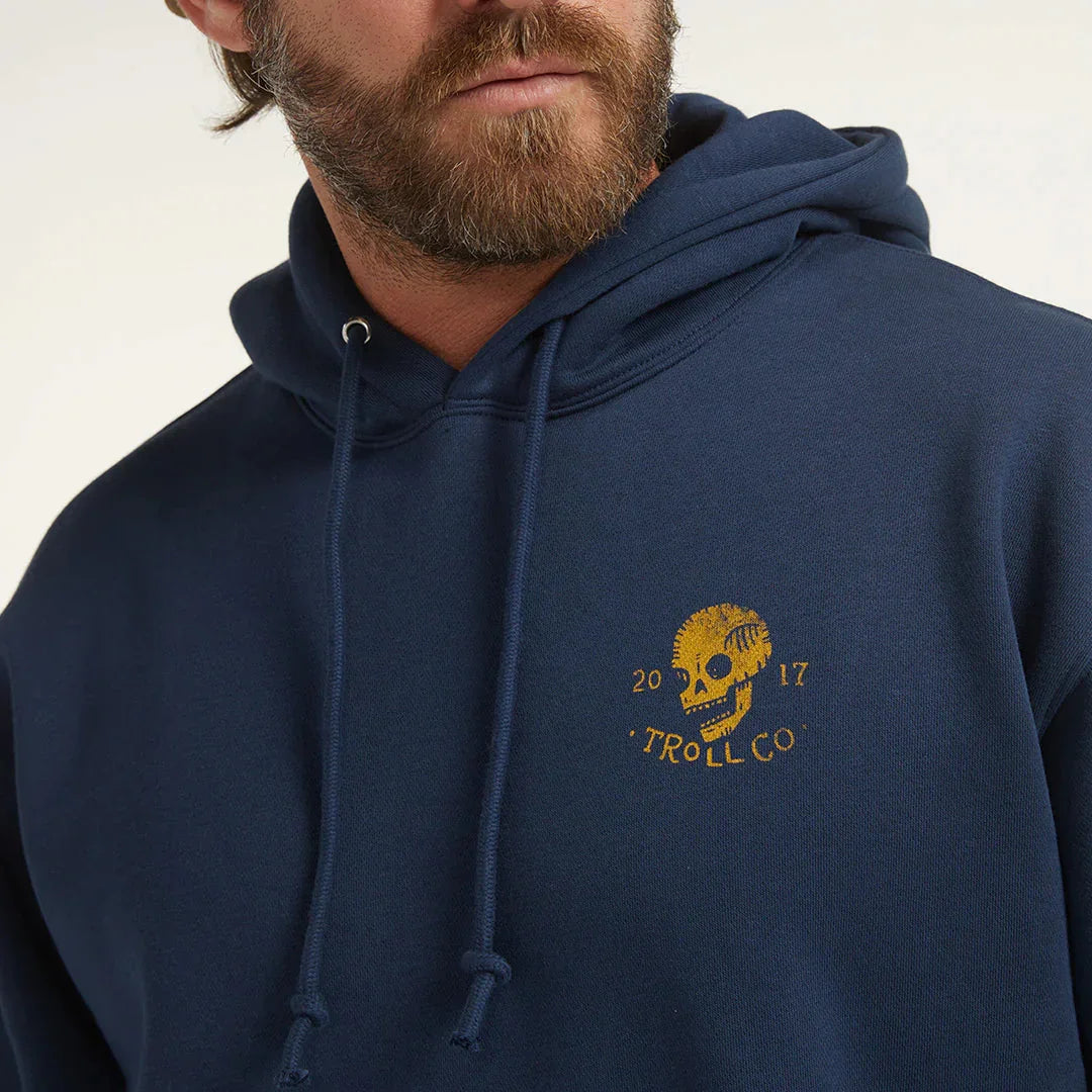 Man in navy blue Troll Co. hoodie with yellow skull graphic logo on chest