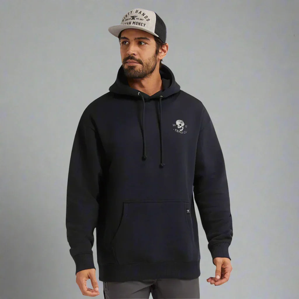 Man wearing black Troll Co. hoodie and trucker hat, gray background