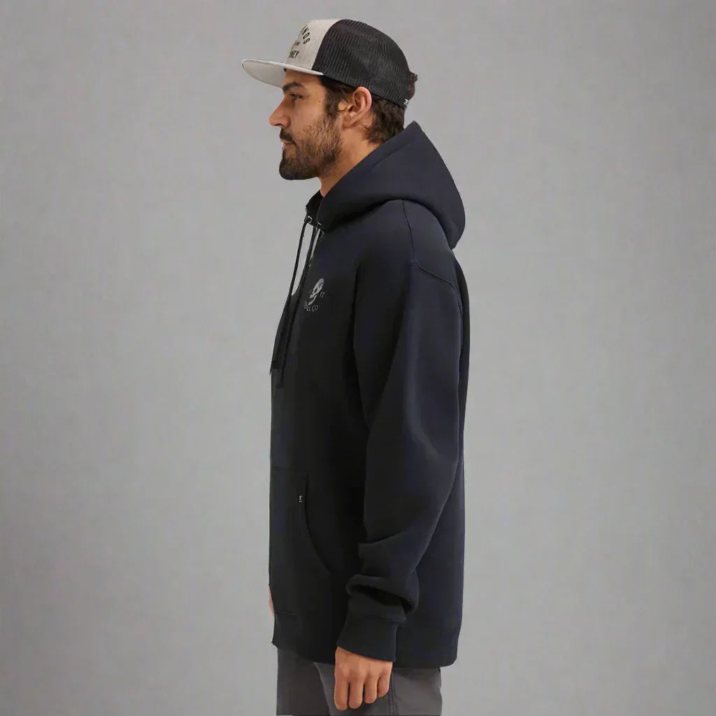 Man in black hoodie and mesh trucker cap standing sideways in studio