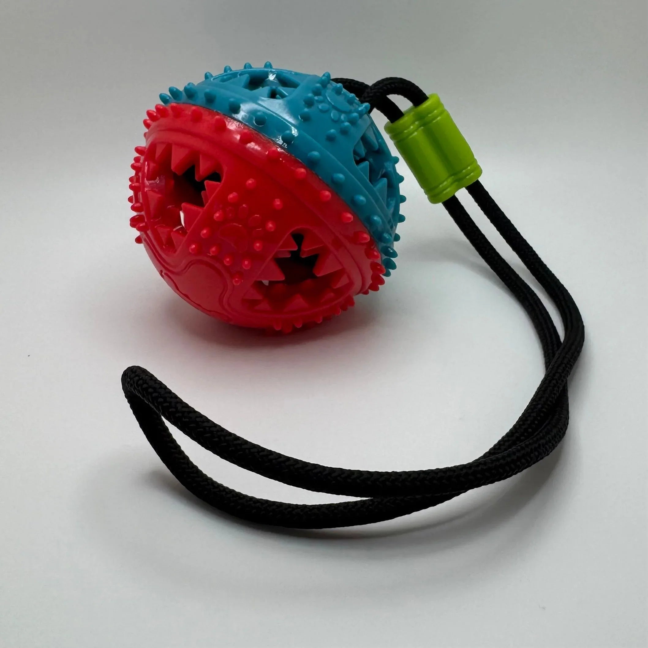 Spiky red and blue rubber dog toy ball with rope handle for pet chewing and tugging