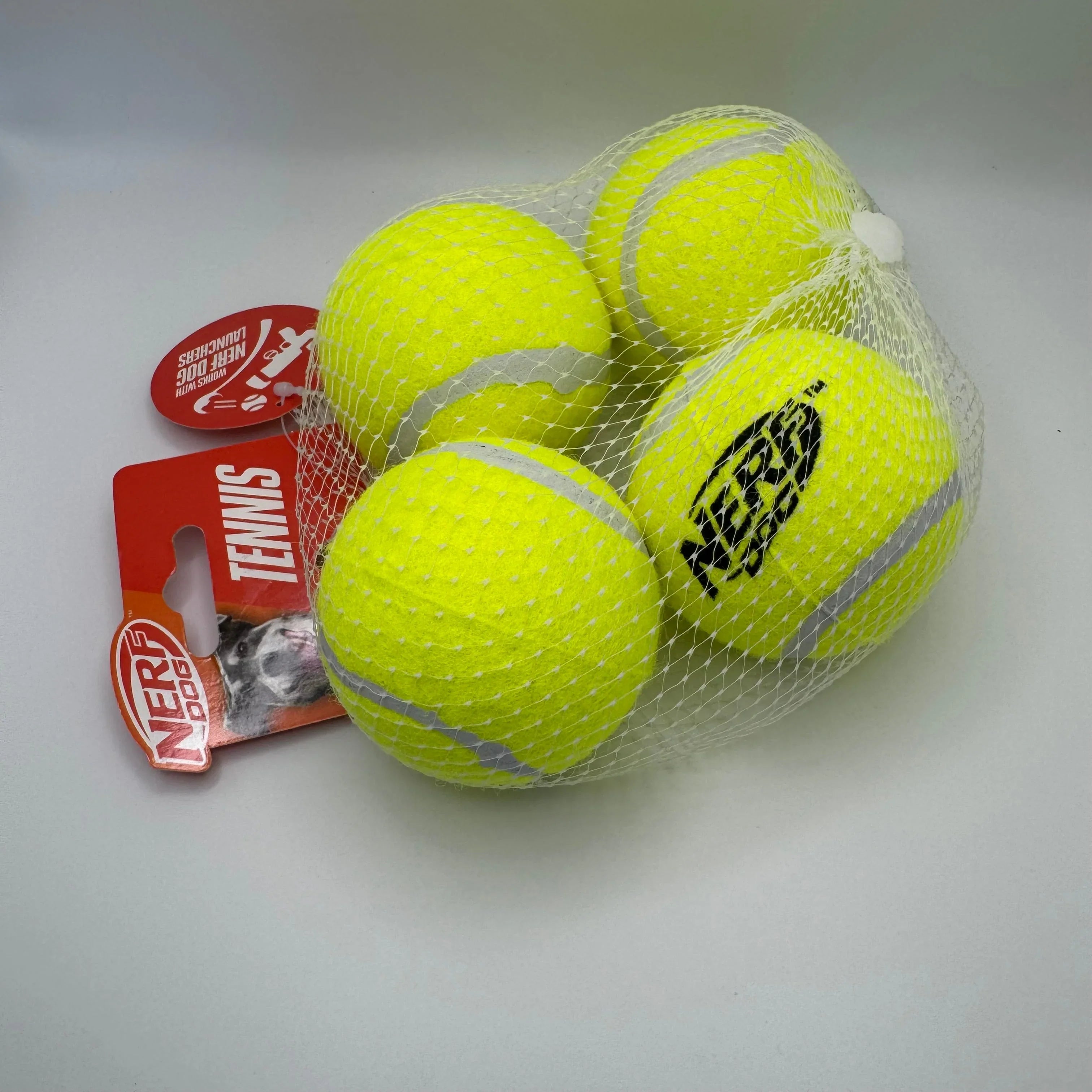 NERF Dog tennis balls for pets in a mesh bag with product tag on white background