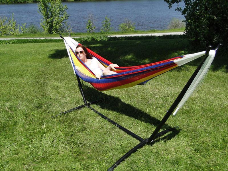 Woman relaxing in colorful Mayan hammock on double universal hammock stand outdoors by water
