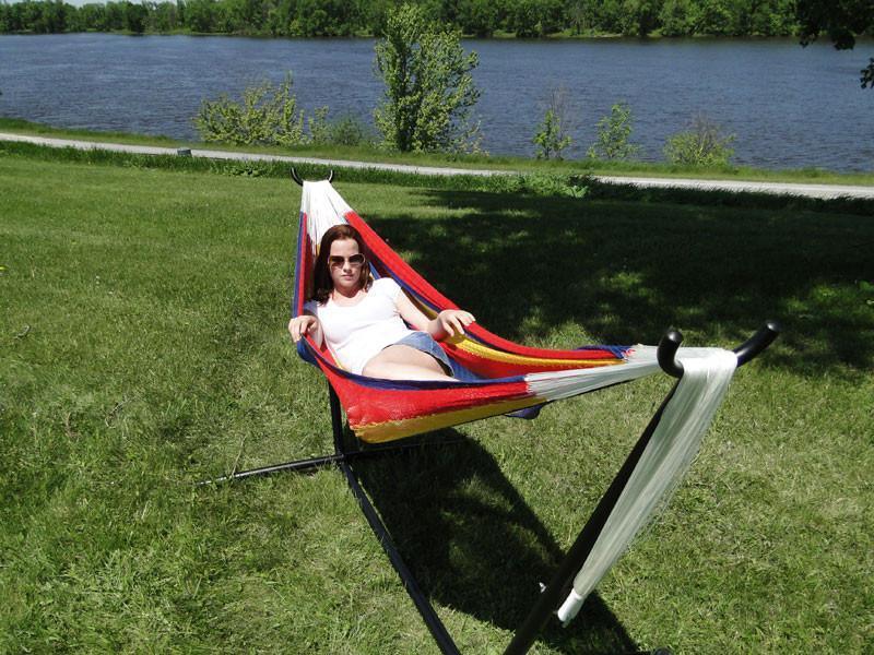 Woman relaxing in a colorful Mayan hammock on a universal stand near a river outdoors