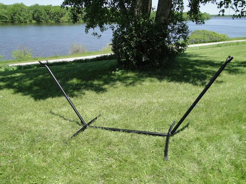 Black universal hammock stand on grass near a lake and trees outdoors