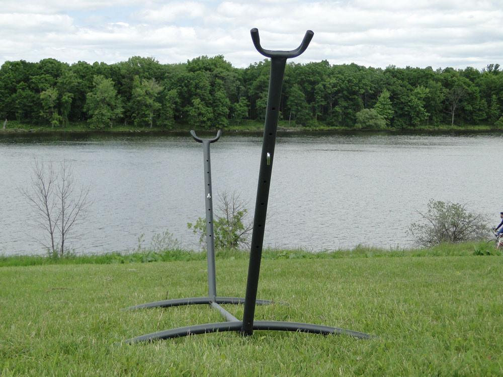 Universal hammock stands on grass by a river with trees in the background outdoors