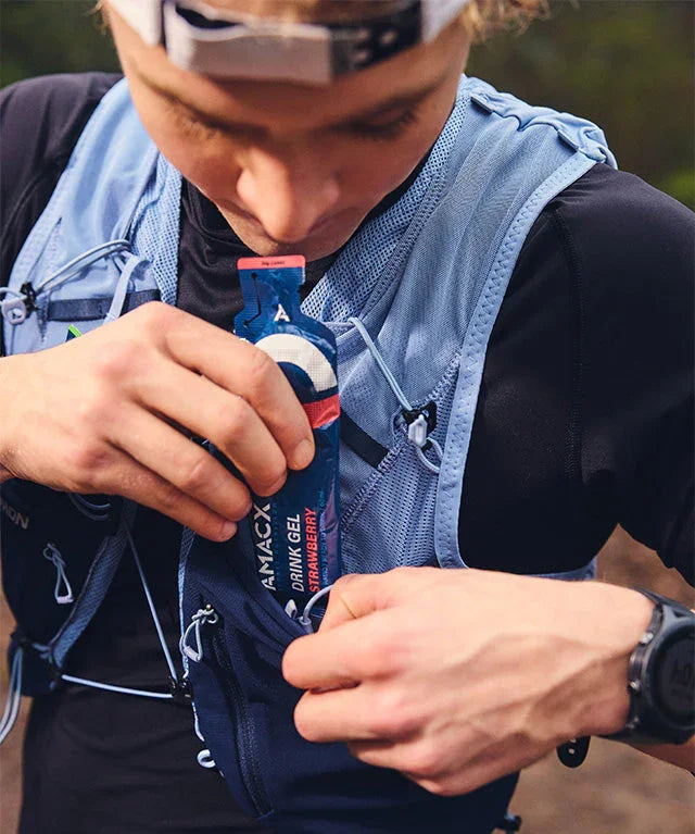 Runner storing strawberry drink gel in hydration vest during outdoor activity