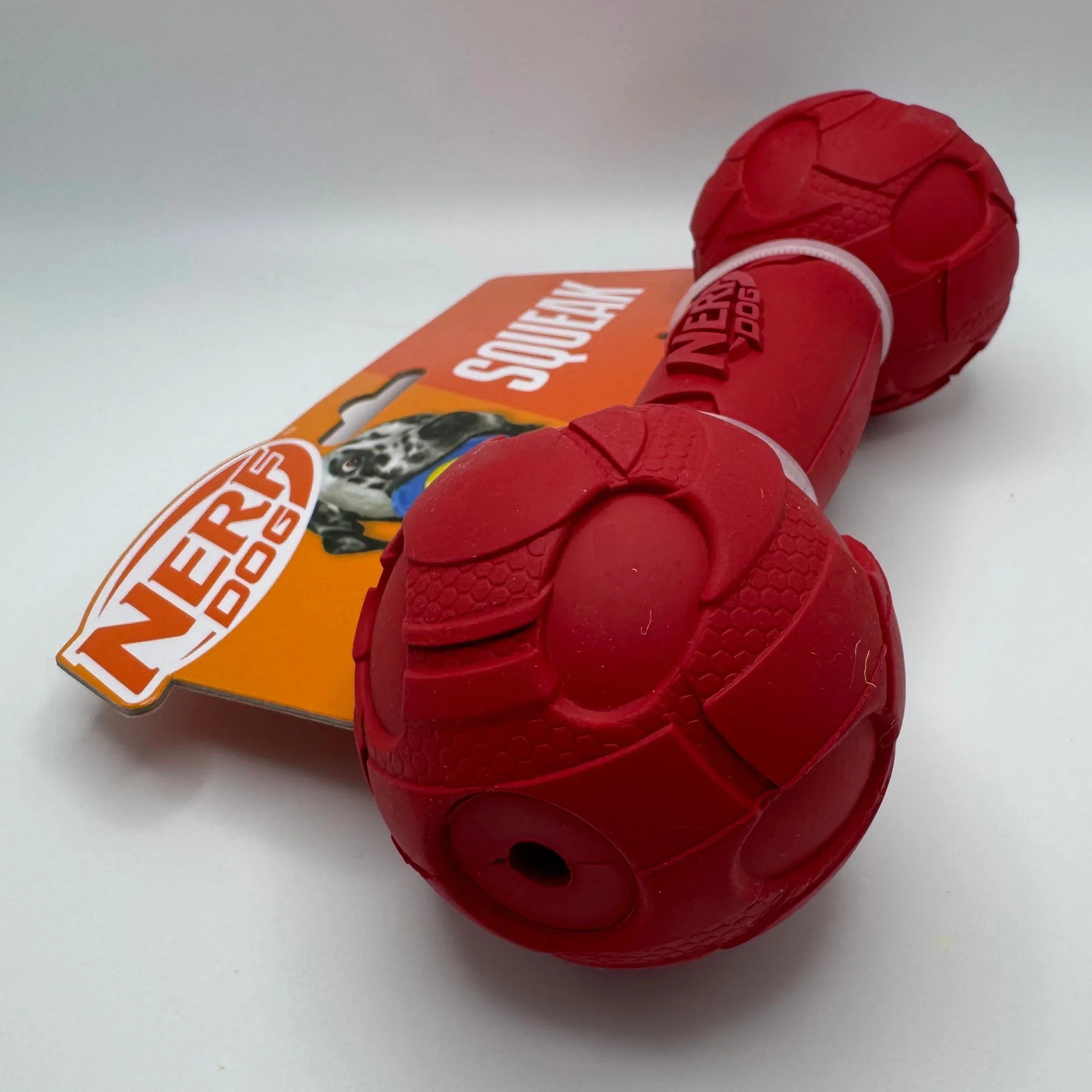 Red Nerf Dog squeaky dumbbell toy for pets with textured surface on white background