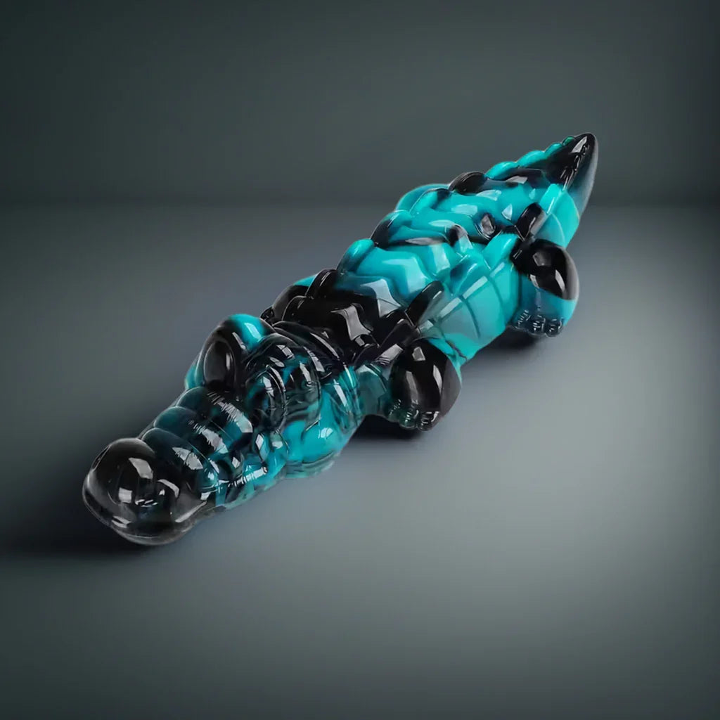 Blue and black crocodile-shaped glass art sculpture on a gray background