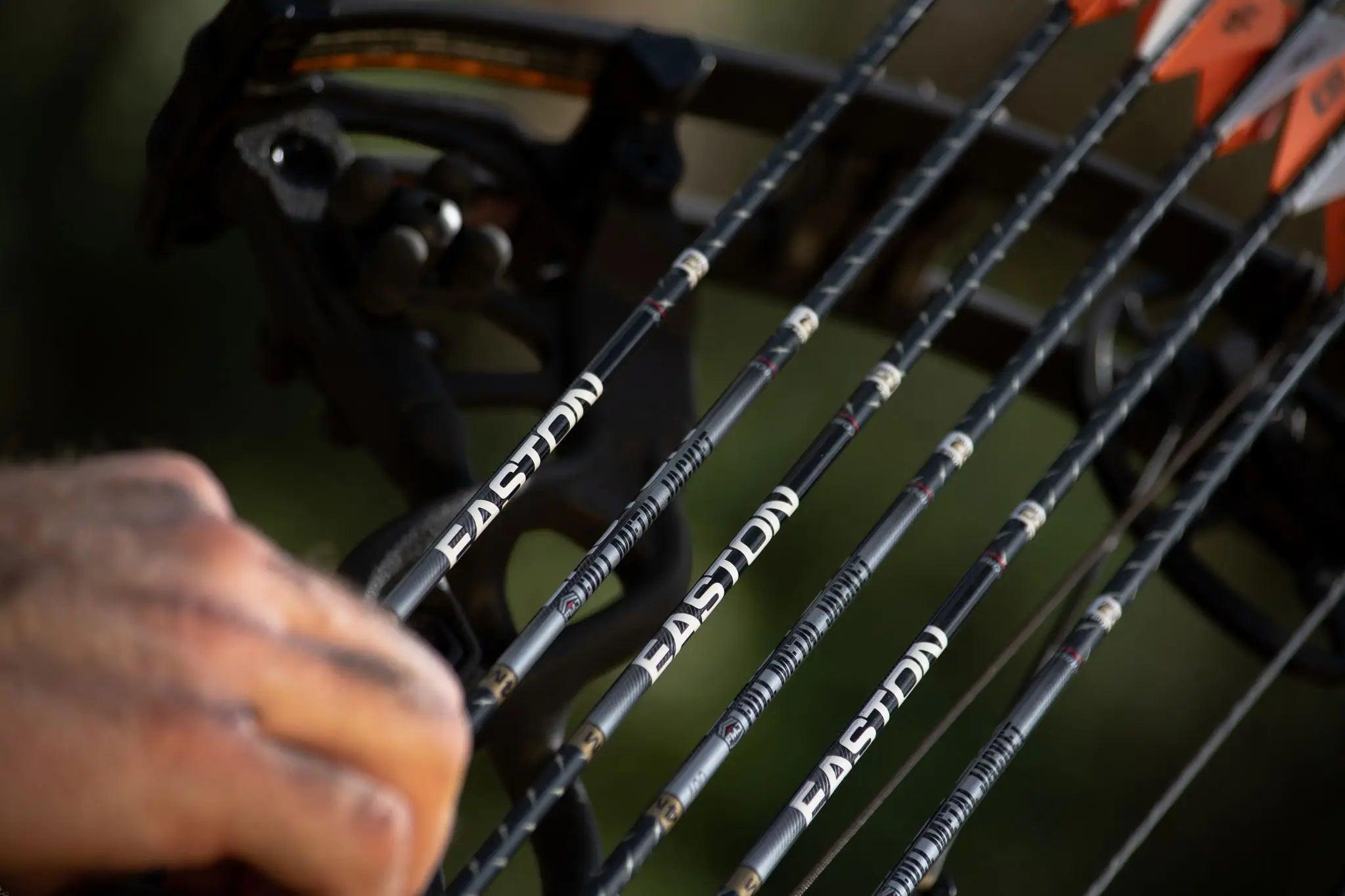 Easton FMJ 4mm carbon arrows on a compound bow with orange fletching, close-up view