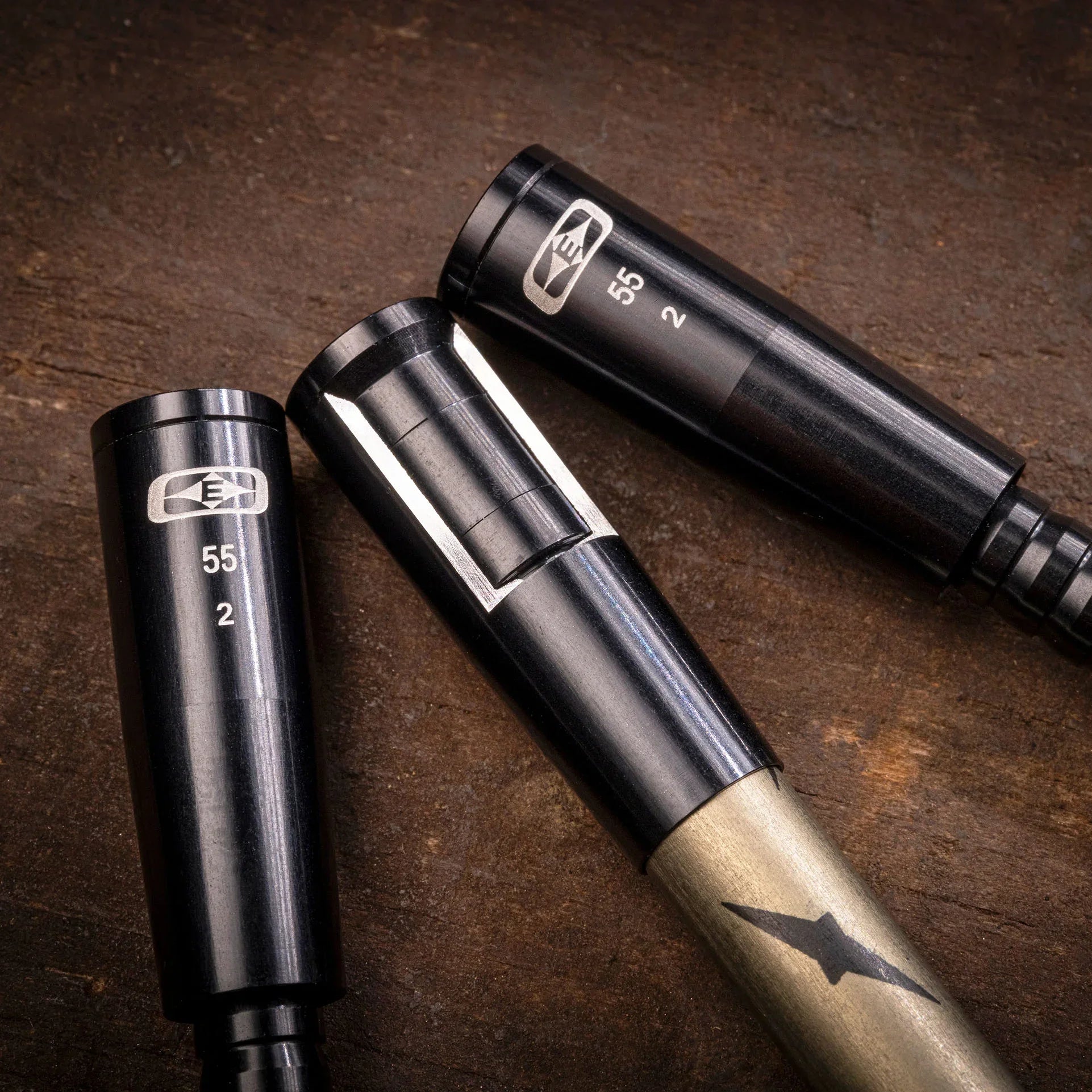 Close-up of three E4 55 2 black metal tool handles on a wooden surface