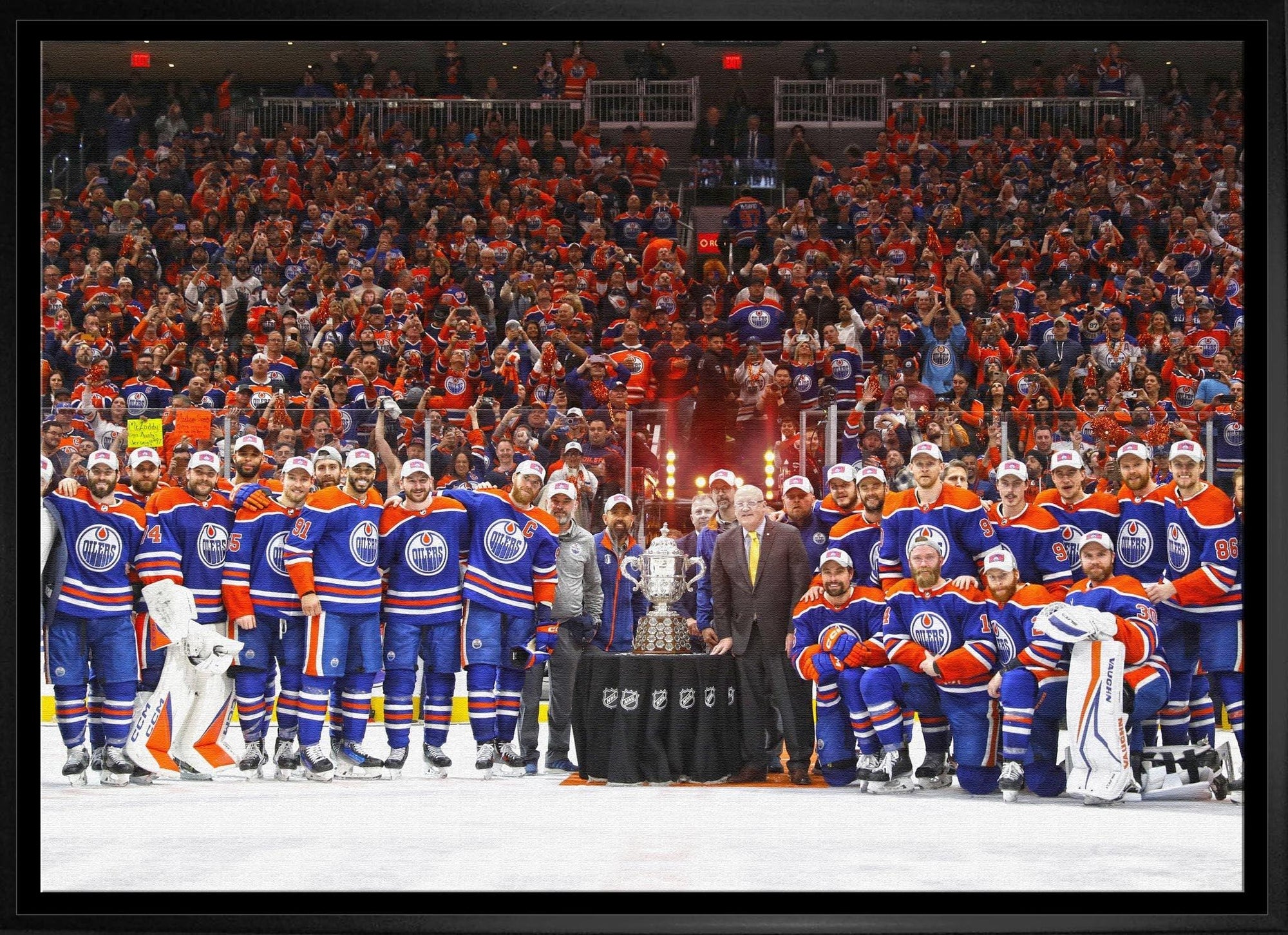 Edmonton Oilers hockey team in blue jerseys celebrating around trophy on ice rink with fans