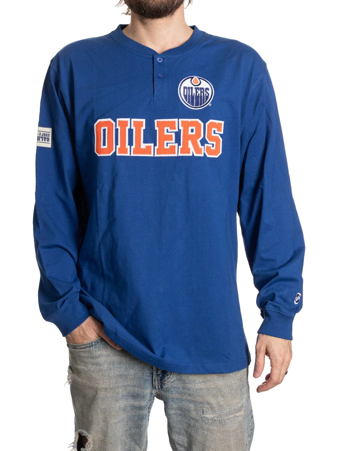 Man wearing blue Edmonton Oilers long sleeve henley shirt and ripped jeans