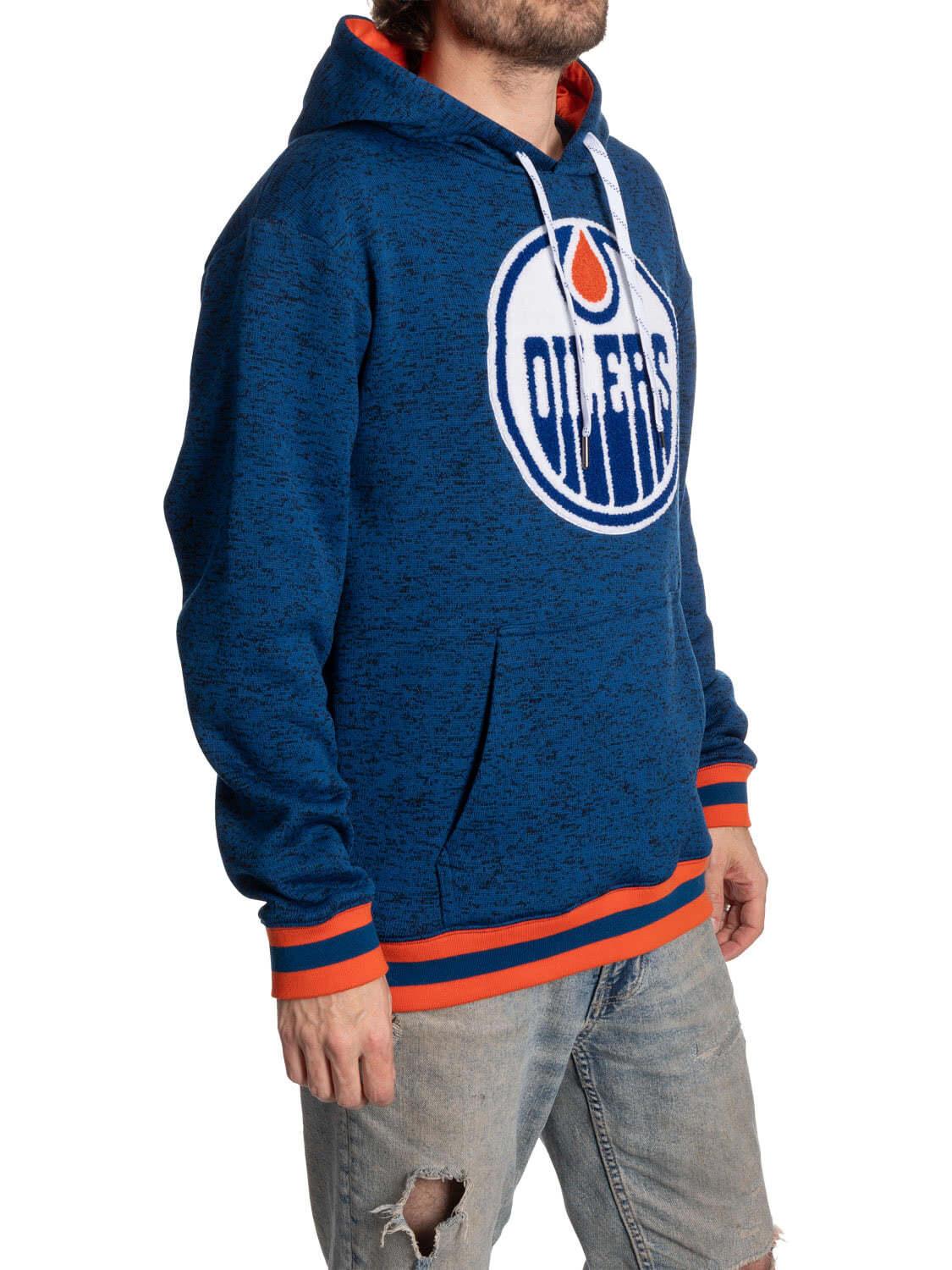 Man wearing blue Edmonton Oilers hoodie with orange accents and ripped jeans