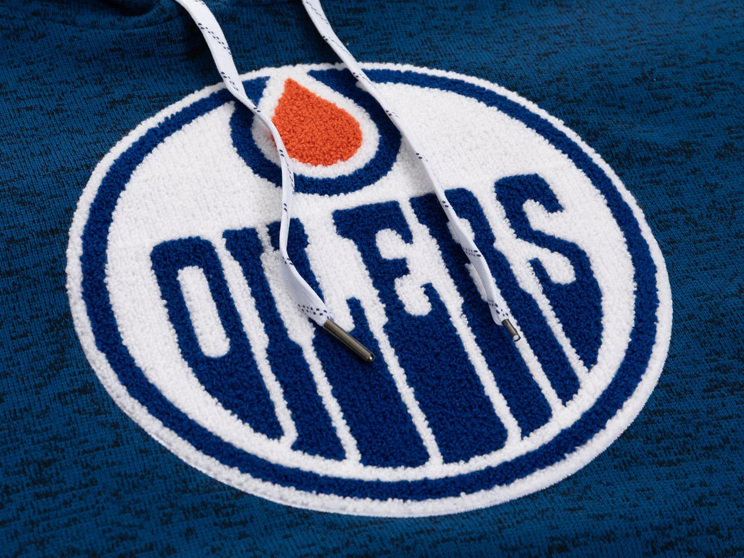 Close-up of Edmonton Oilers logo patch on blue textured hoodie with white drawstrings