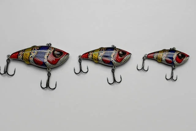 Three colorful segmented fish fishing lures with treble hooks on white background