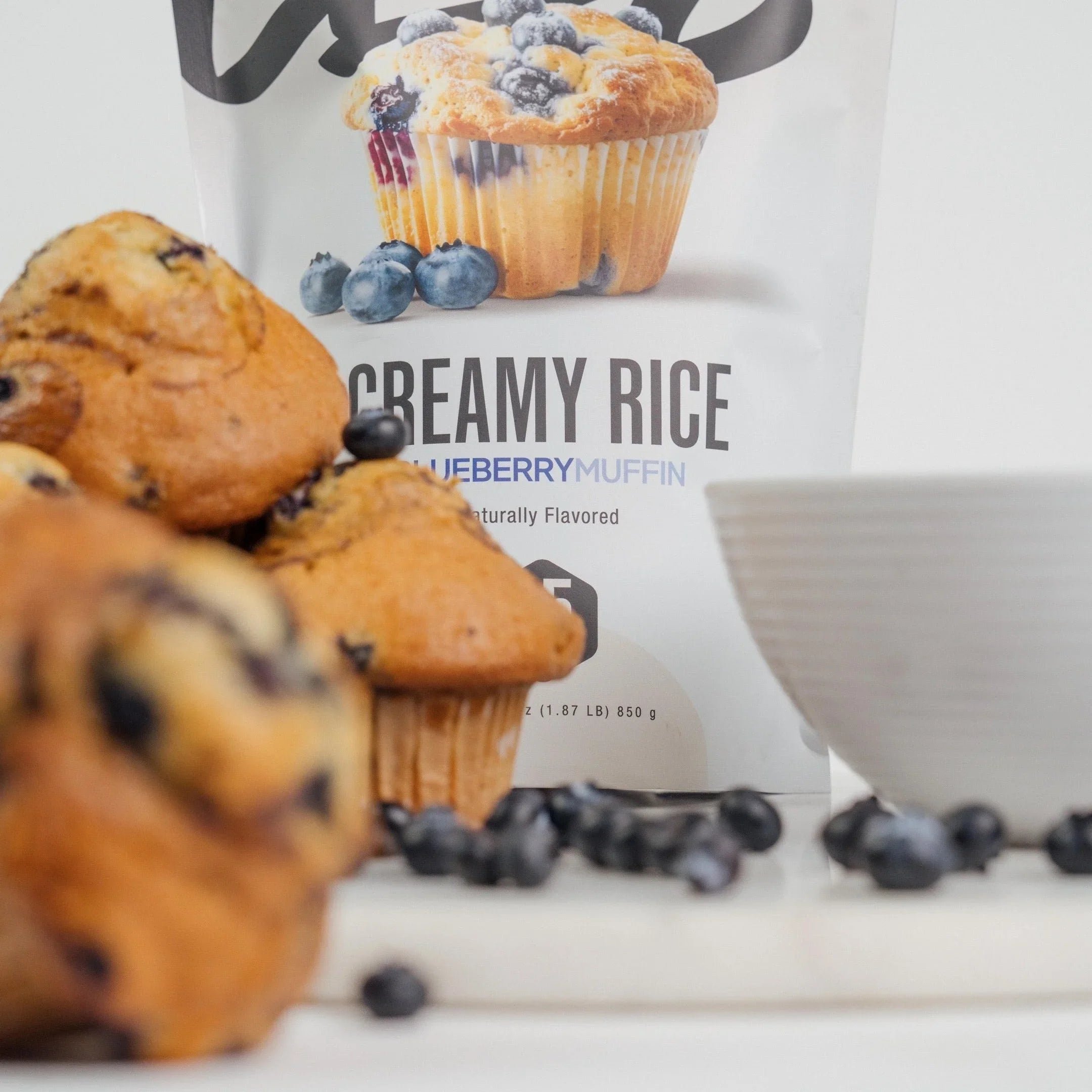 Blueberry muffins and fresh blueberries with Creamy Rice Blueberry Muffin mix on a white background