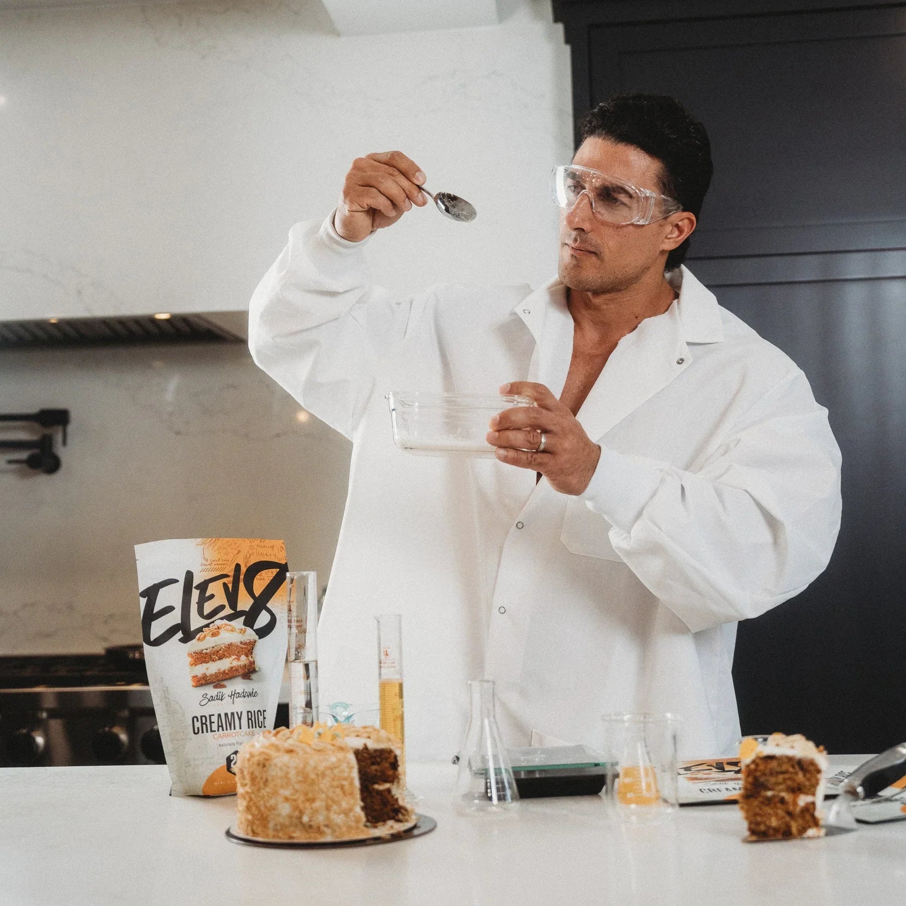 Man in lab coat with Elev8 Creamy Rice, baking cake in modern kitchen