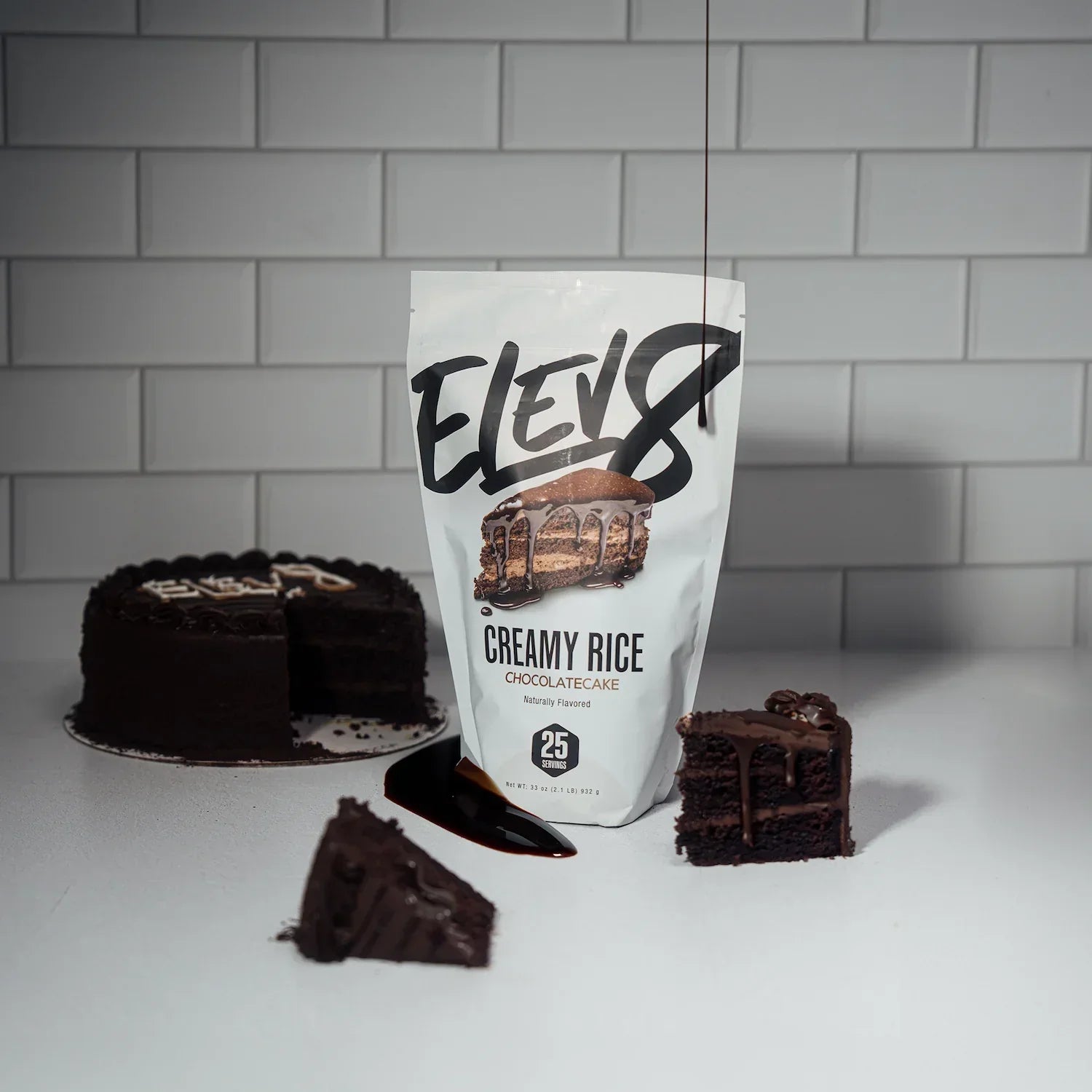 Elev8 Creamy Rice Chocolate Cake protein mix pouch with chocolate cake slices on white counter