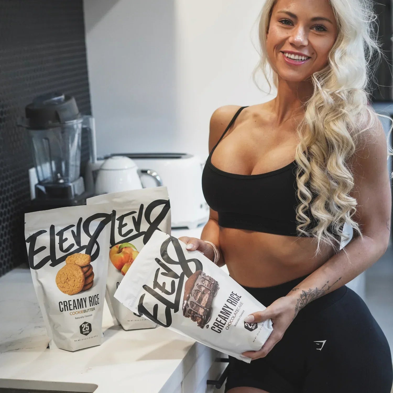 Woman in athletic wear holding Elev8 Creamy Rice protein powder in modern kitchen