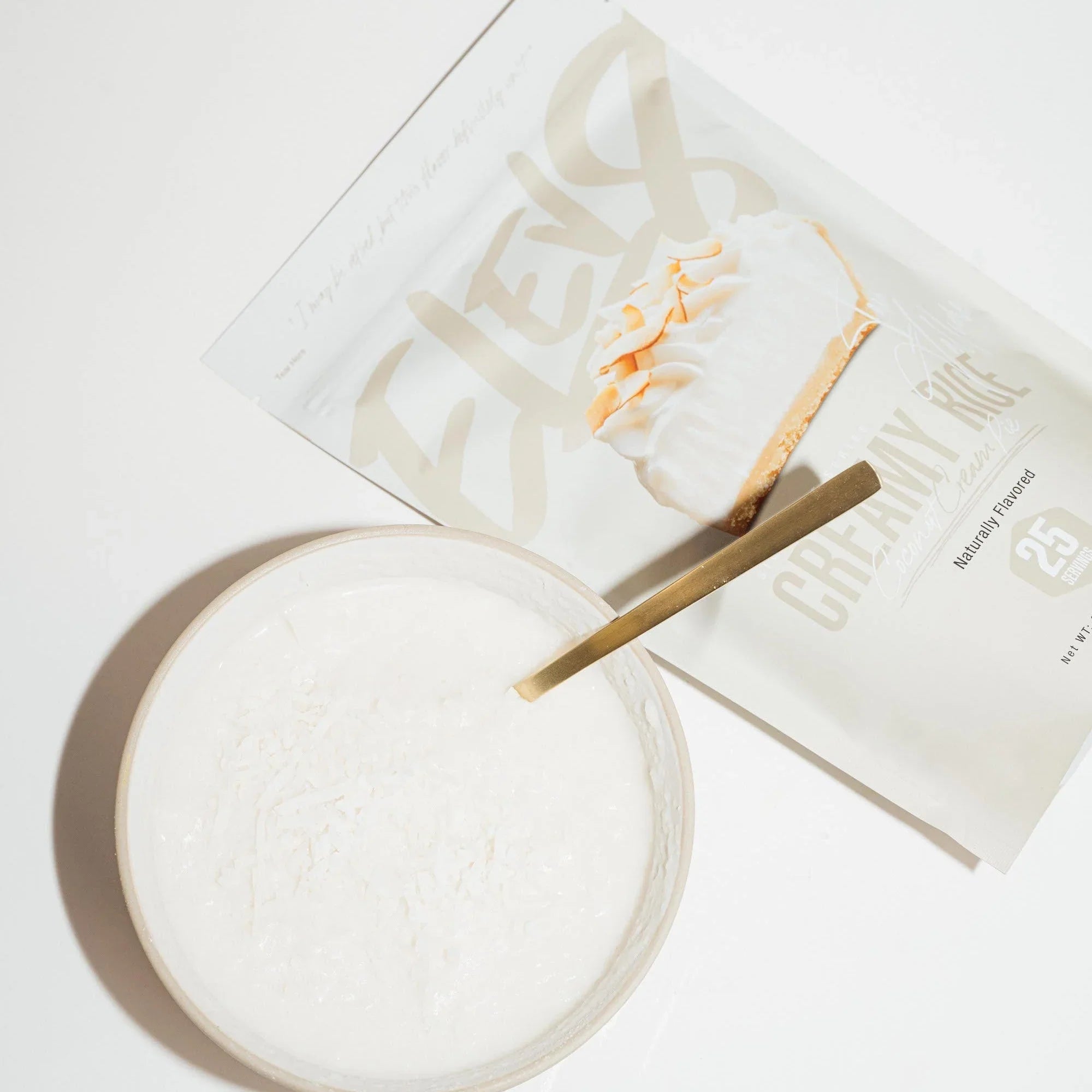 Bowl of creamy rice pudding with gold spoon next to ELEV8 Creamy Rice protein mix packet