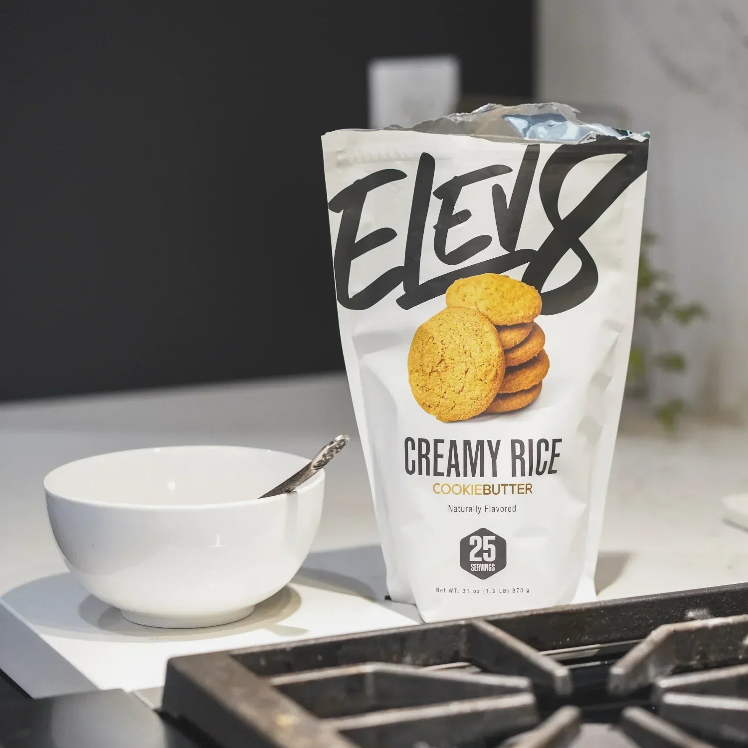 Elev8 Creamy Rice Cookie Butter cereal bag with bowl and spoon on kitchen counter