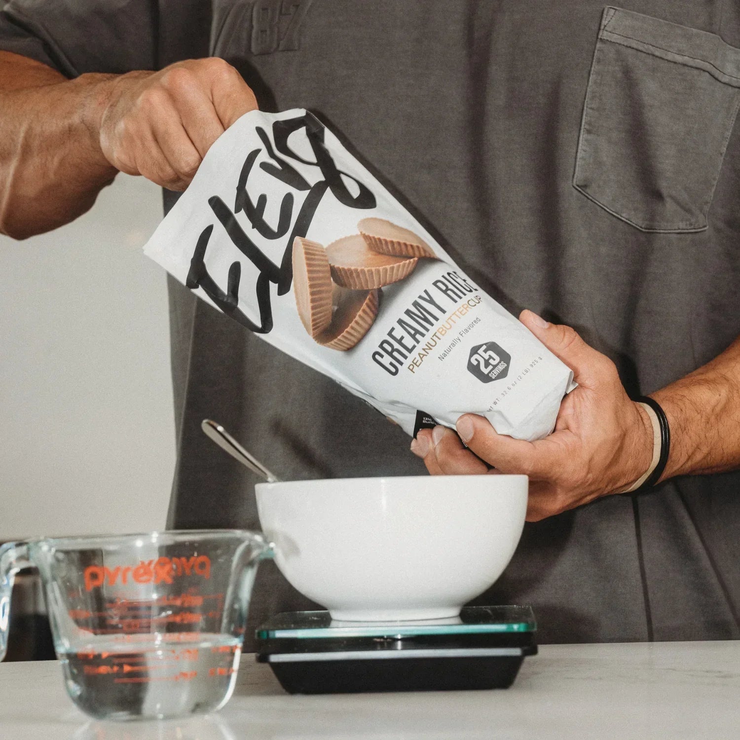 Man preparing ELEV8 Creamy Rice Peanut Butter protein powder next to a bowl and measuring cup