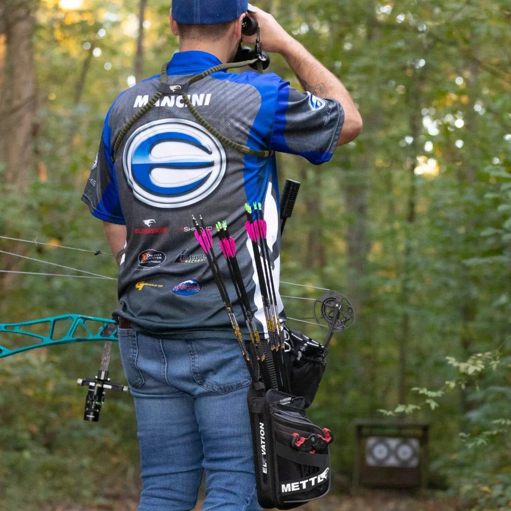 Archer in blue jersey with arrows and compound bow in forest archery range