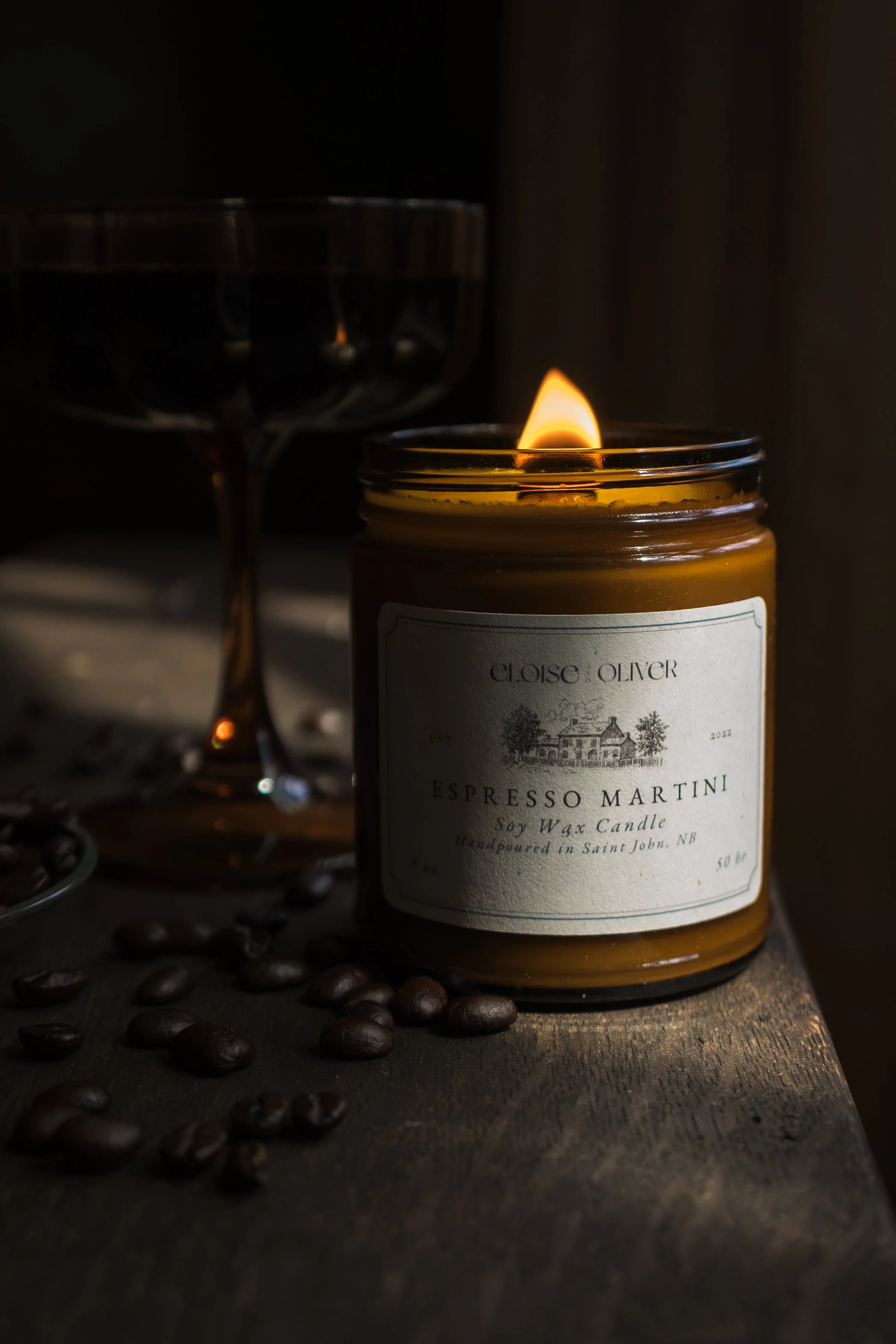 Espresso Martini soy wax candle burning on wooden table with coffee beans and a dark glass