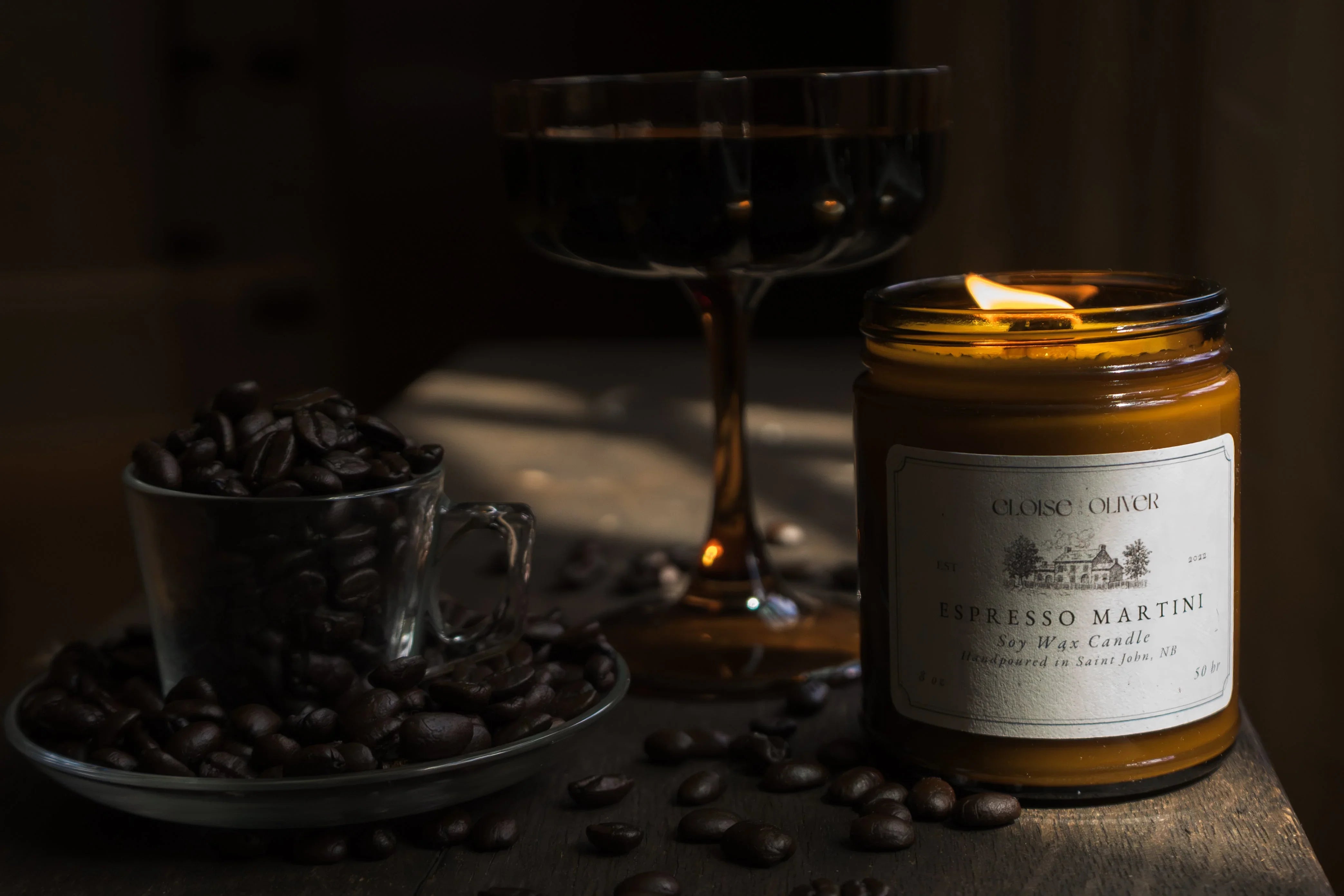 Espresso Martini candle, coffee beans in glass cup, and dark cocktail on wooden table