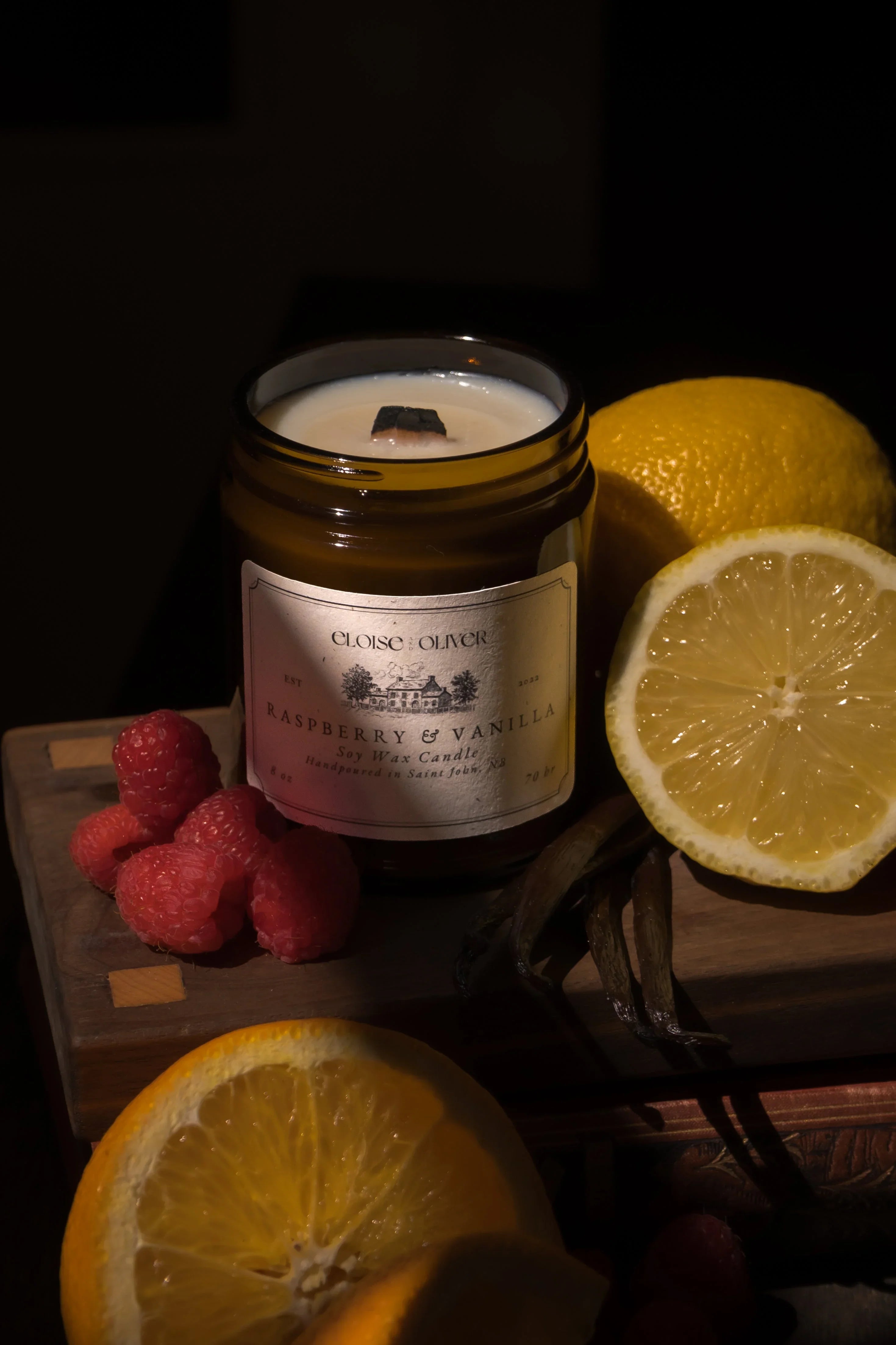 Raspberry and vanilla soy wax candle with fresh raspberries, vanilla beans, and sliced lemon