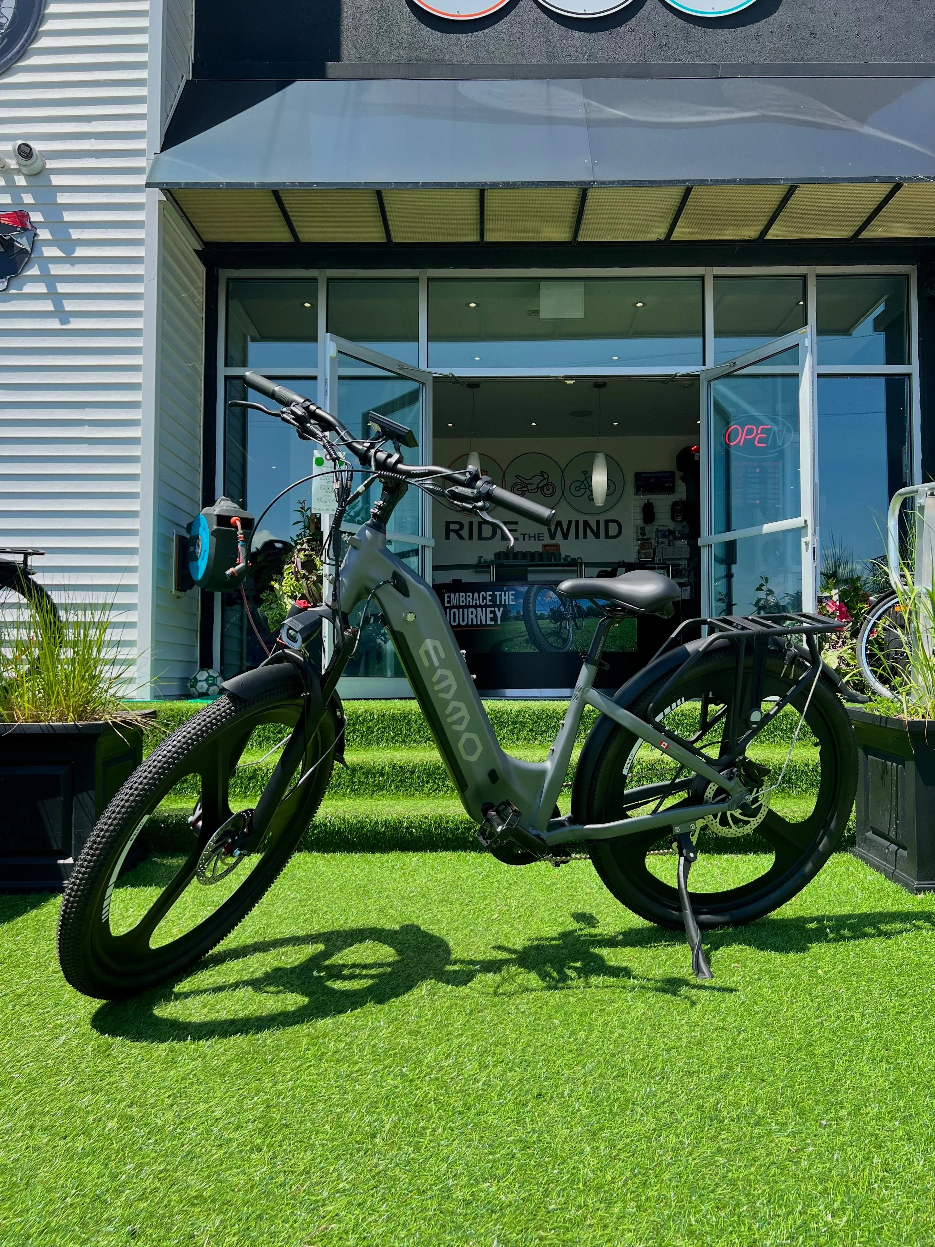 Emmo electric bike parked on artificial grass in front of a modern bike shop entrance