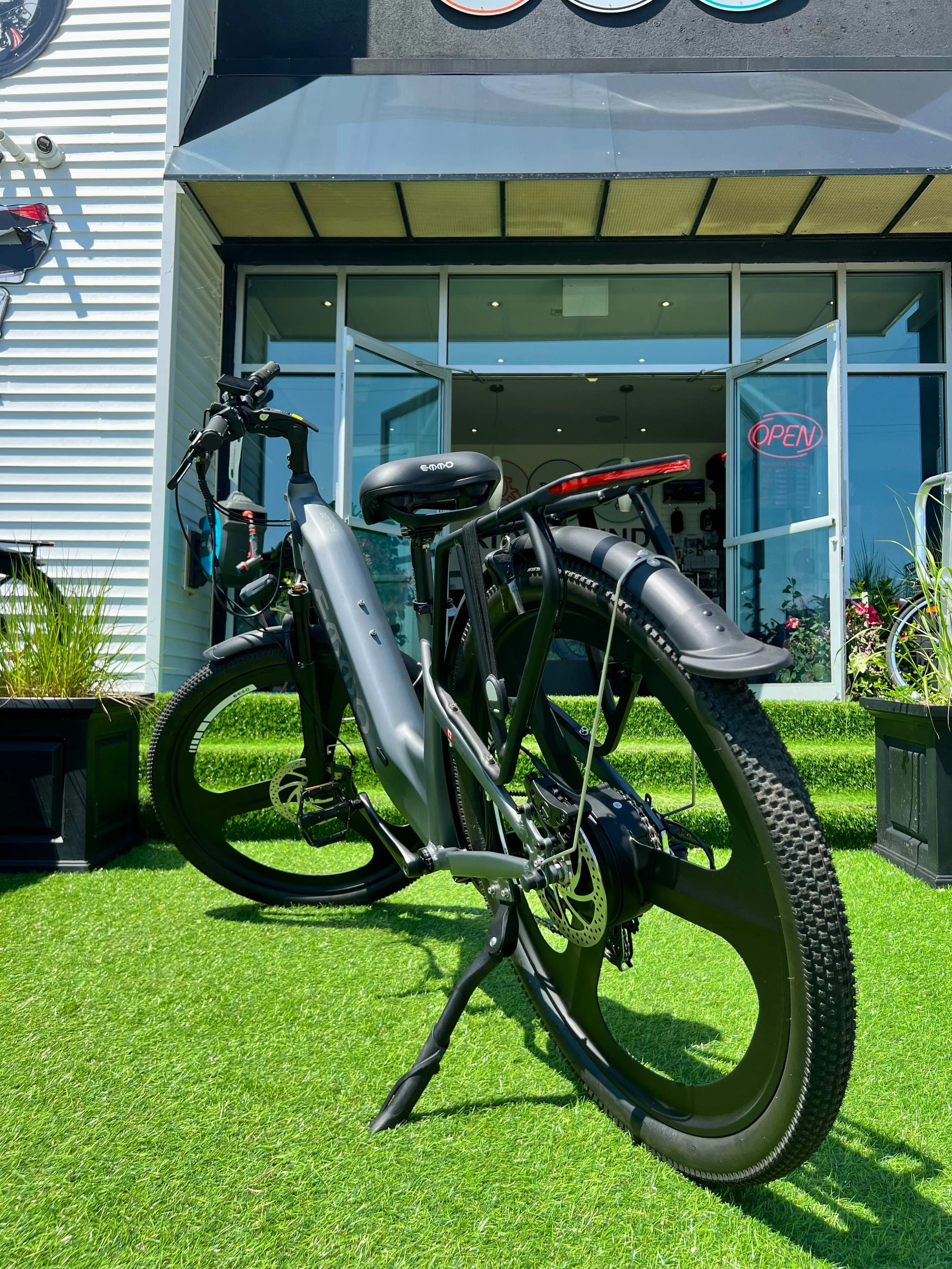 Electric bike with thick tires parked on artificial grass outside an e-bike shop with open doors