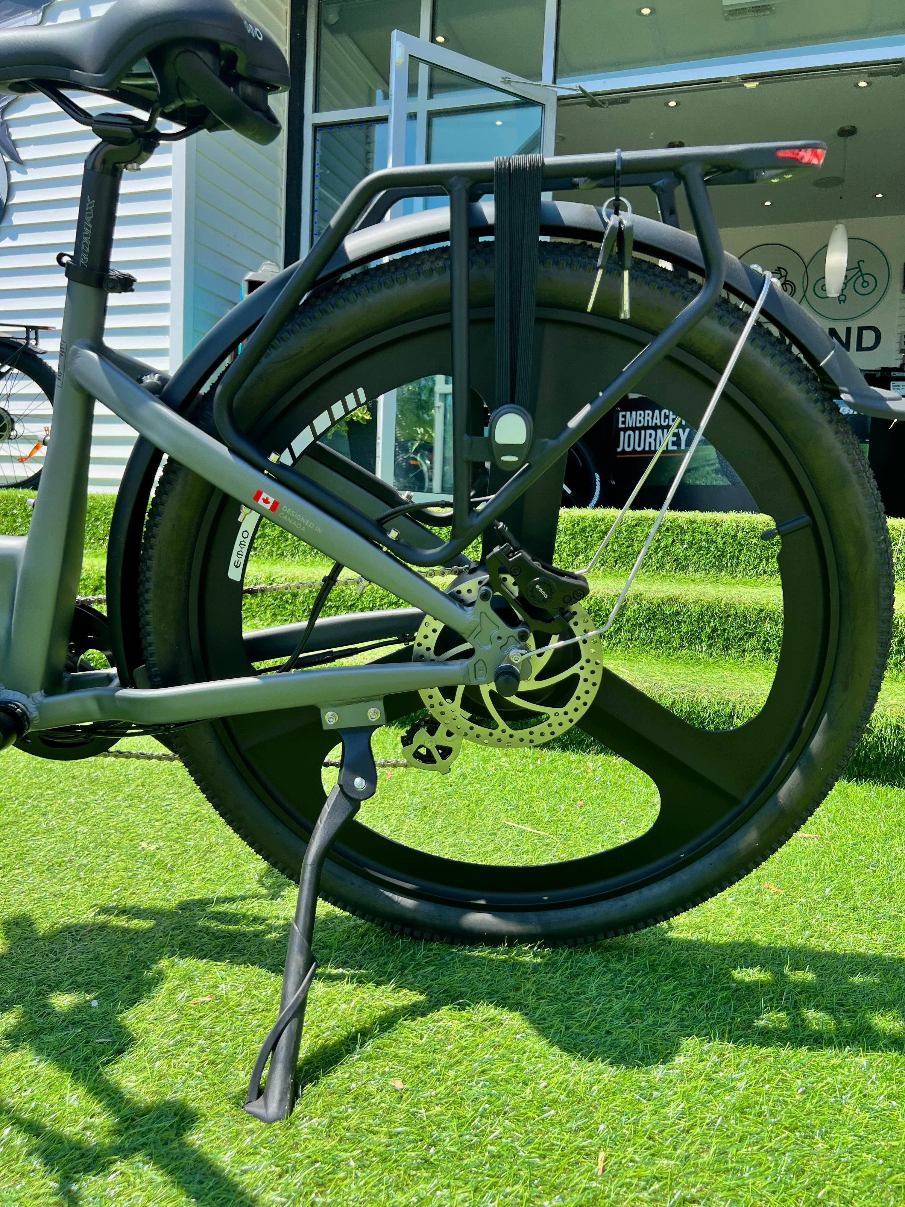 electric bike rear wheel with disc brake, cargo rack, and kickstand on green grass