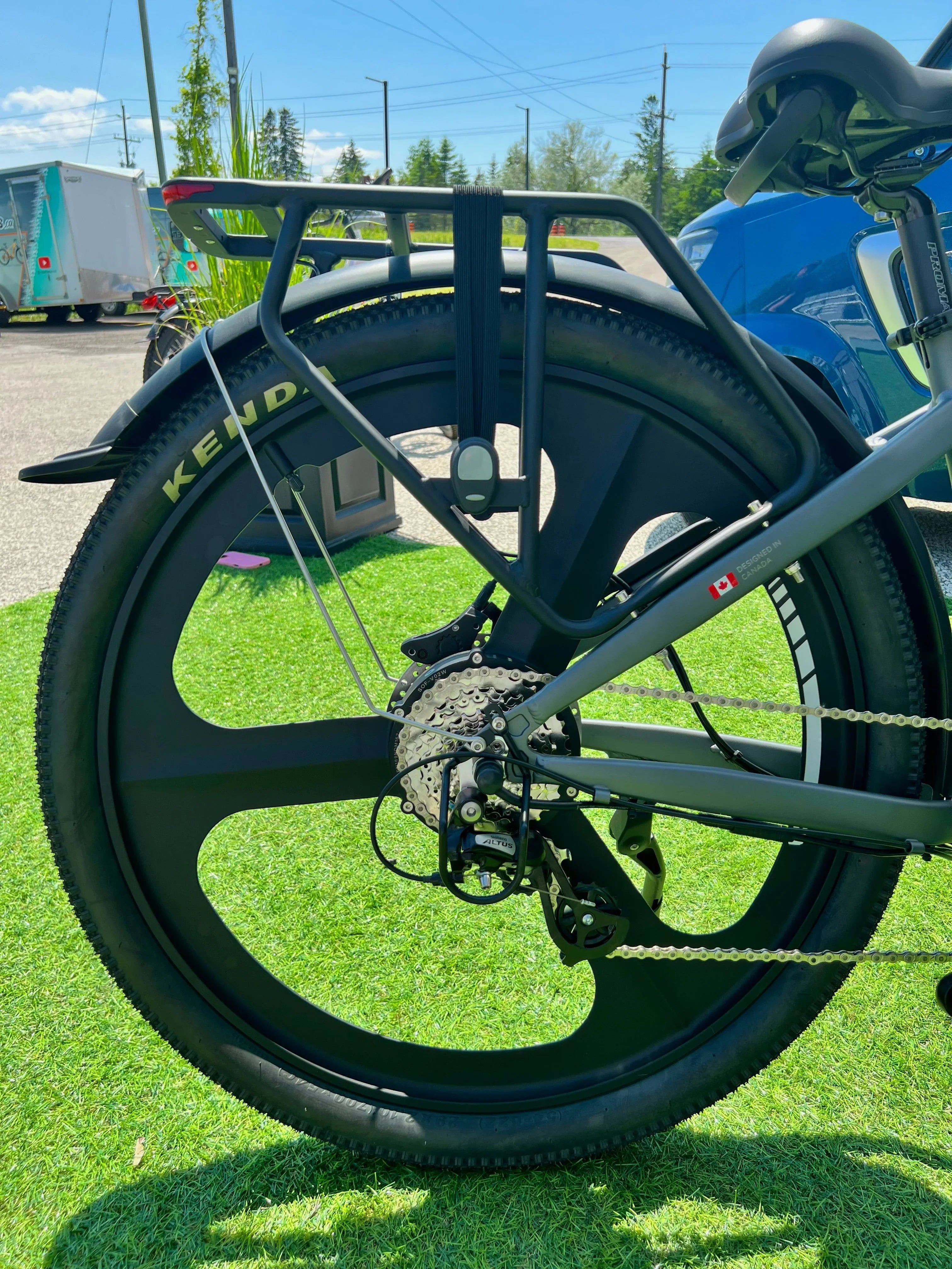Rear view of electric bike wheel with five-spoke rim, Kenda tire, and cargo rack outside