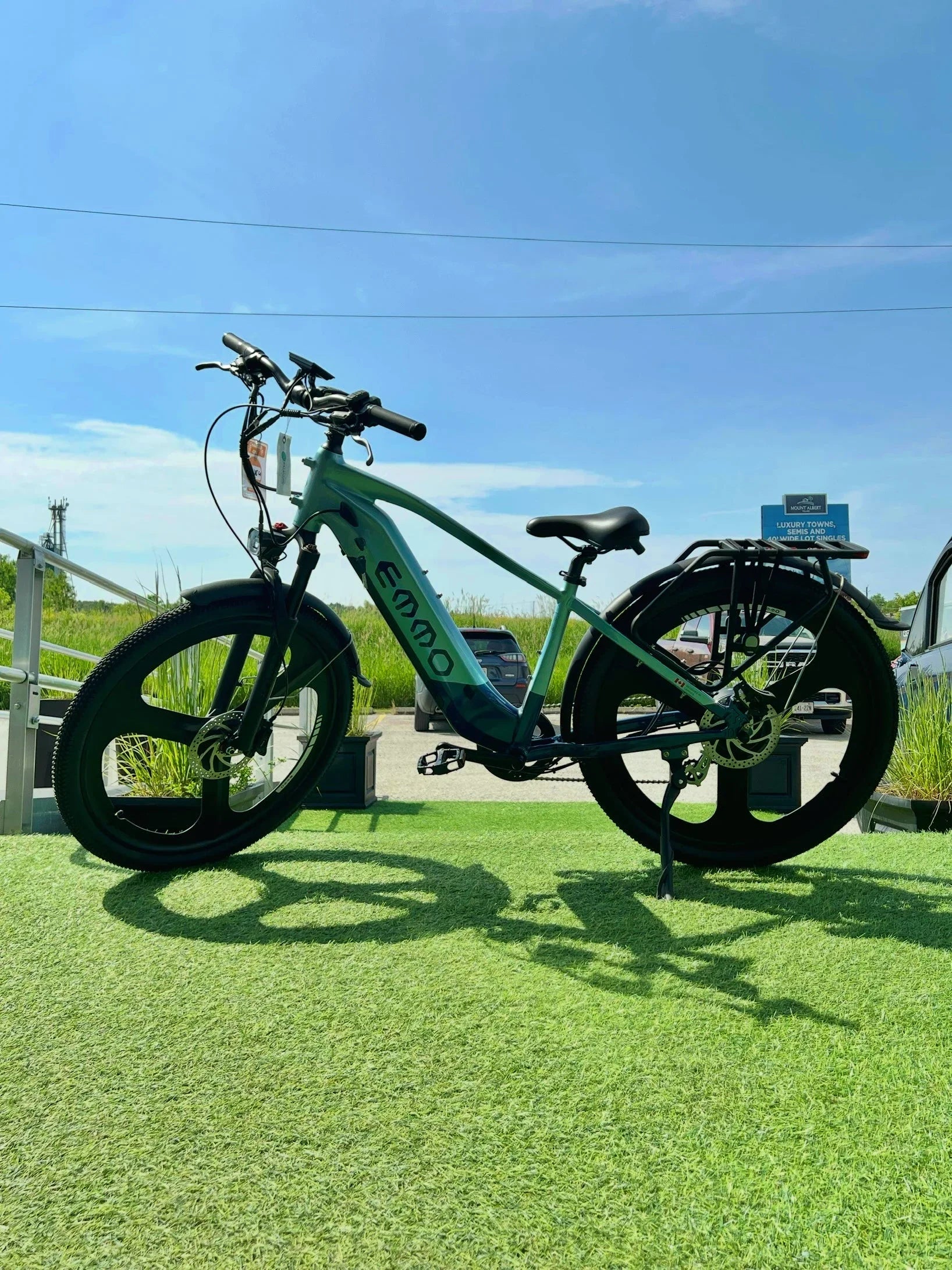 EMMO electric bike with fat tires on green grass under blue sky, outdoor summer setting