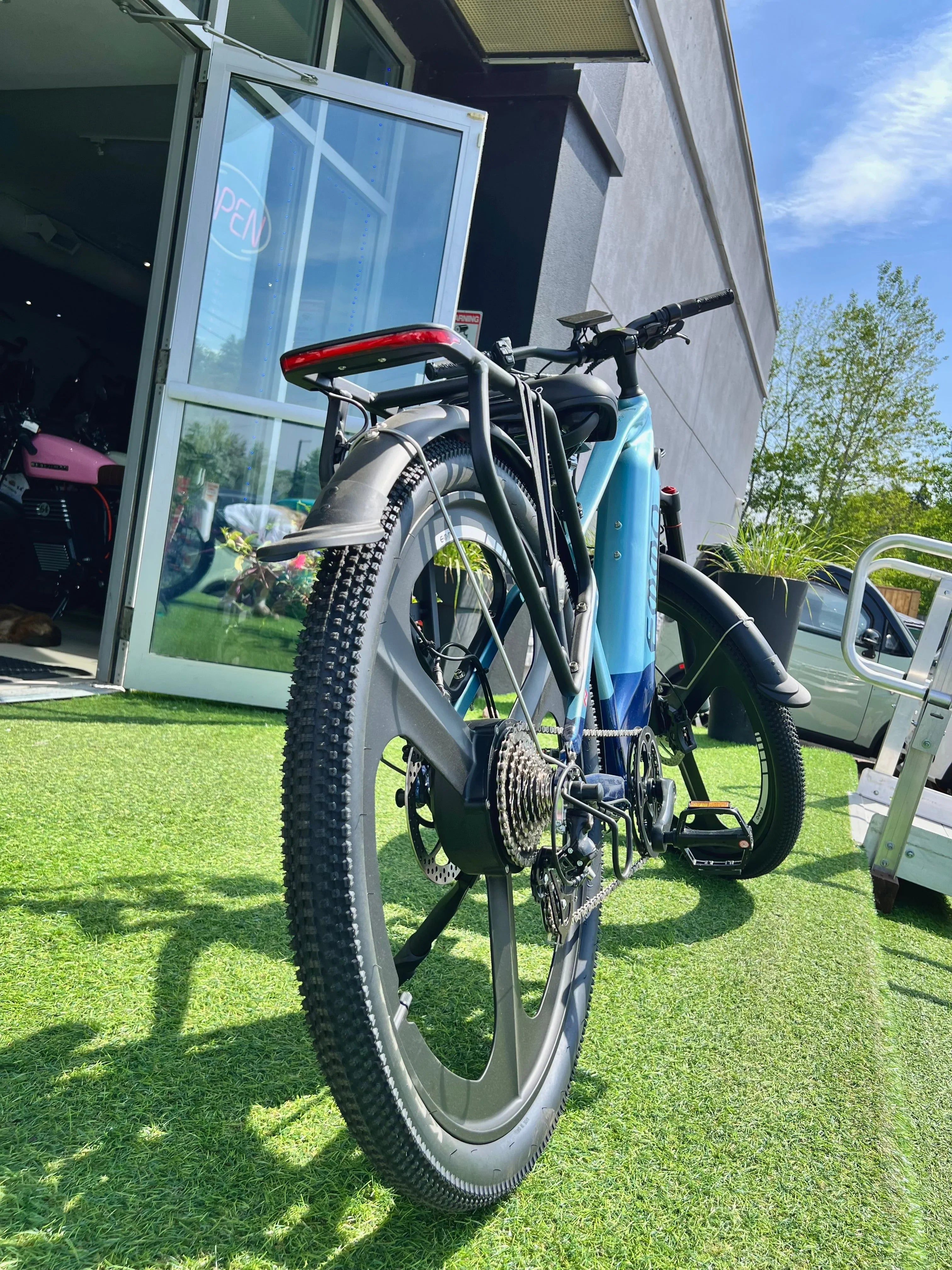 Modern electric bike with fat tires outside shop on artificial grass, sunny day