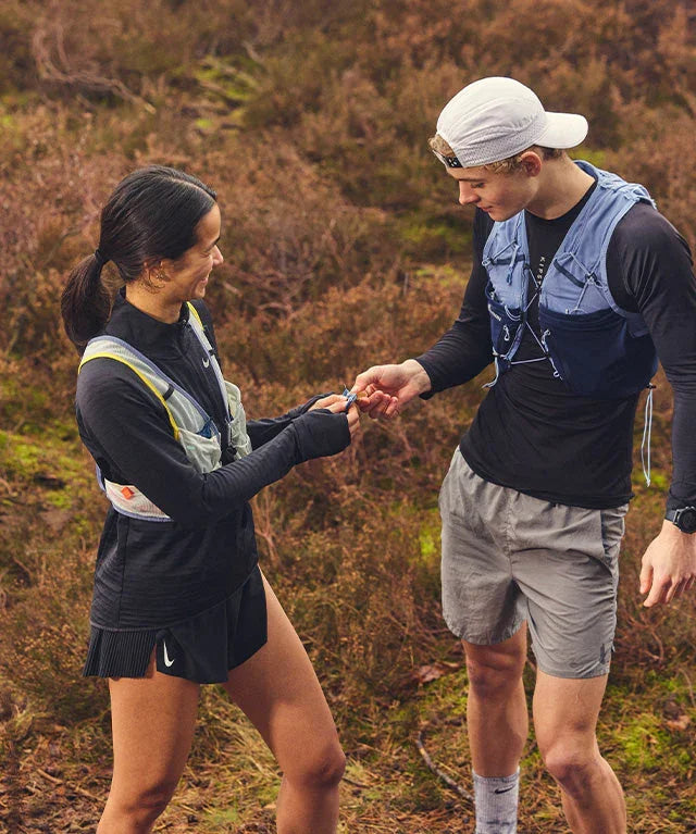 Two trail runners sharing energy fruit chew snack outdoors on a forest trail