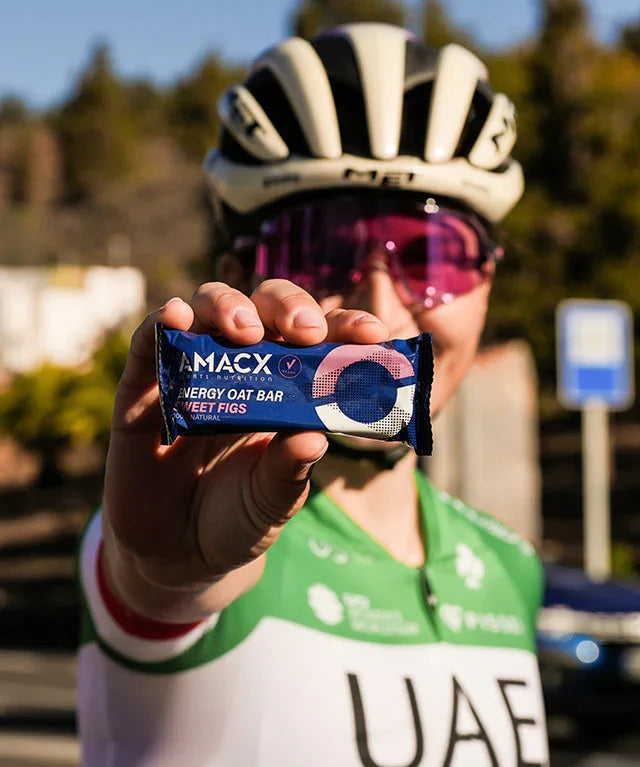 Cyclist in UAE jersey holding AMACX Energy Oat Bar Sweet Figs outdoors