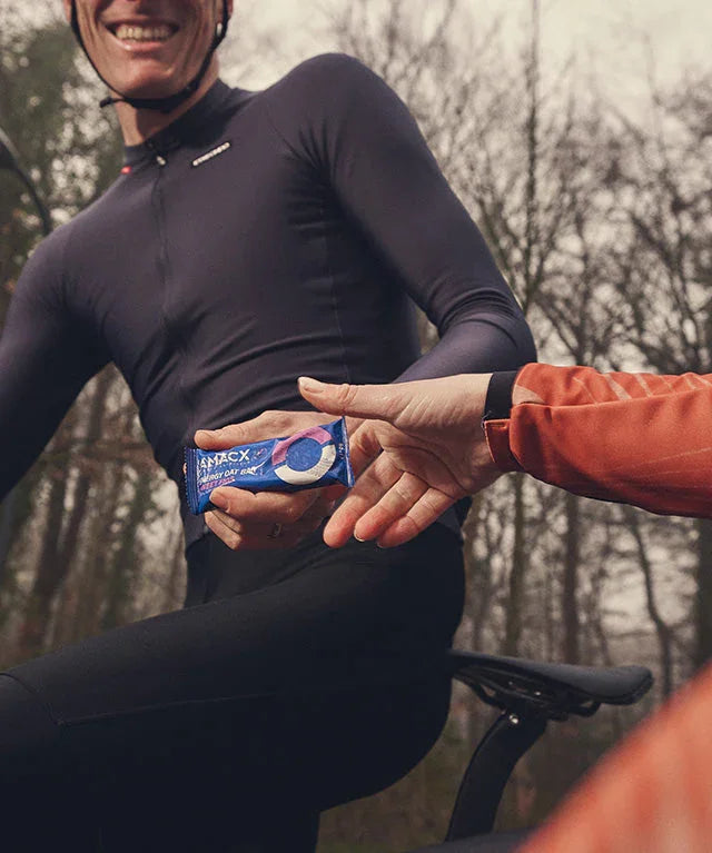 Cyclist outdoors receiving an Oatbar sweet figs energy oat bar snack on a bike ride