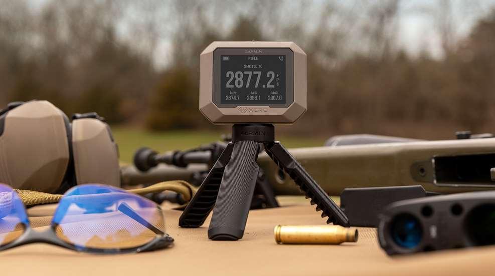 Garmin Xero C1 Pro chronograph on tripod at outdoor shooting range with eyewear and gear